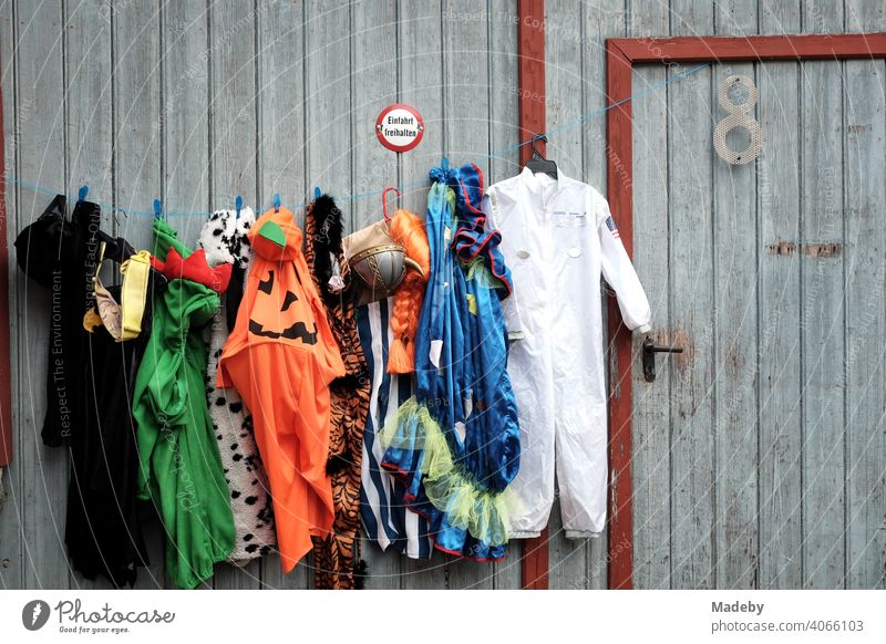 Bunte Kleider und Kostüme an einem alten grauen Scheunentor auf dem Flohmarkt bei den Golden Oldies in Wettenberg Krofdorf-Gleiberg bei Gießen in Hessen Mode