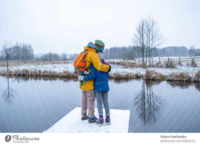 Rückansicht von Vater mit Tochter in der Natur im Winter Kind Vaterliebe Liebe See umarmend Zusammensein Rücken Pflege Vaterpflege genießen Papa Glück Baum