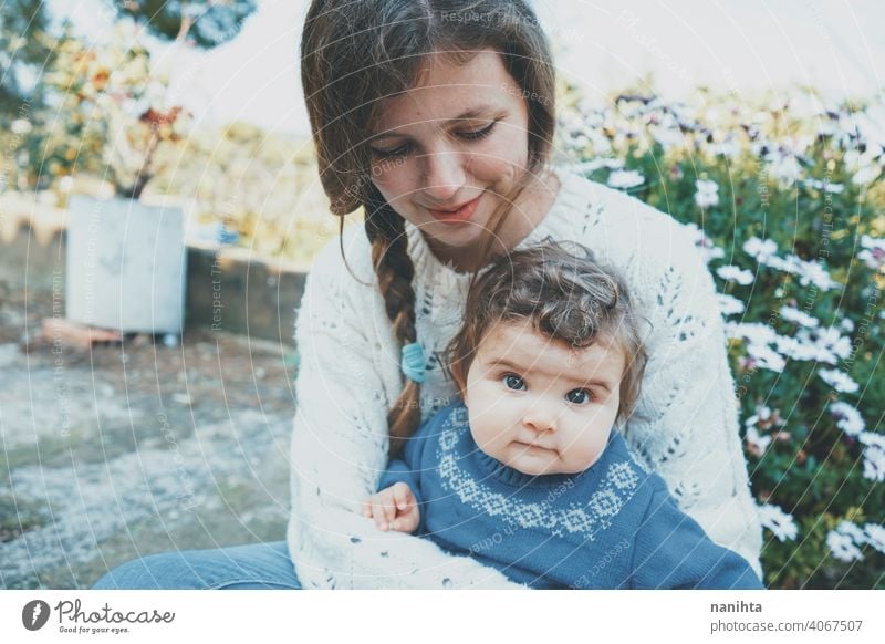 Junge Mutter umarmt ihr Baby und genießt einen Frühlingstag im Garten Familie Mama Lifestyle Liebe Pflege Kind Kindheit Blumen Natur natürlich Hippie im Freien