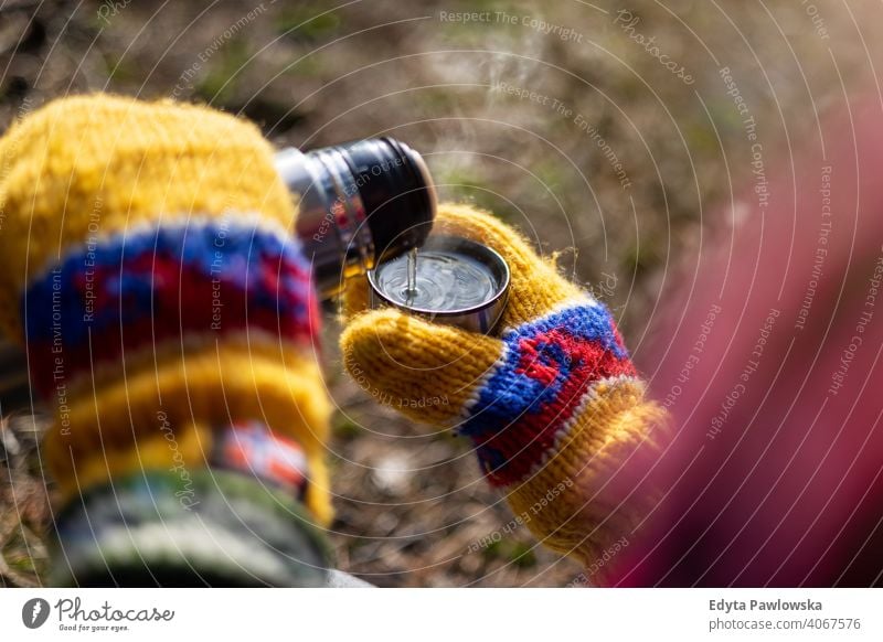 Hände in bunten Fäustlingen gießen ein heißes Getränk aus Thermoskanne Winter warm skandinavisch Handschuhe Waldgebiet Heißgetränk Wetter Wanderung Frau Flasche