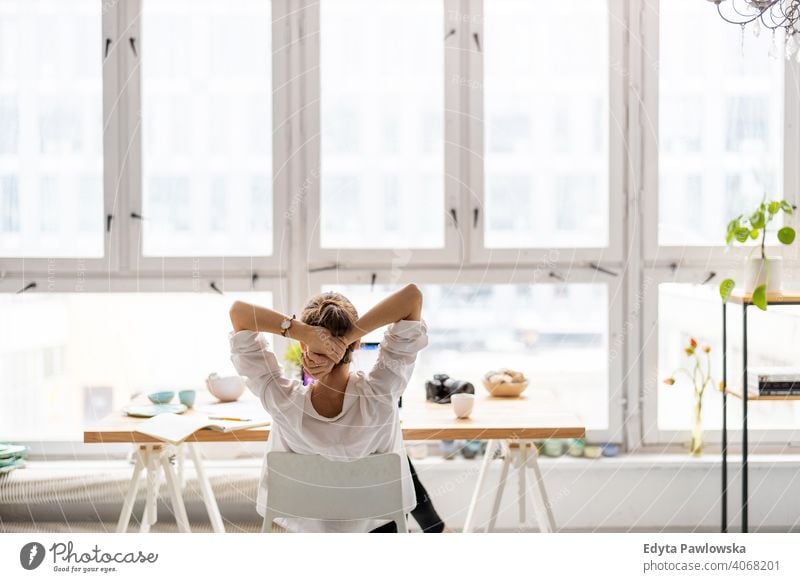 Rückansicht einer jungen Frau, die in einem Loft-Büro an einem Laptop arbeitet Jahrtausende Schüler Hipster im Innenbereich Fenster natürlich Mädchen