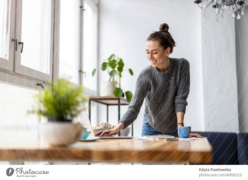 Kreative junge Frau arbeitet am Laptop in ihrem Studio Jahrtausende Schüler Hipster im Innenbereich Loft Fenster natürlich Mädchen Erwachsener eine attraktiv