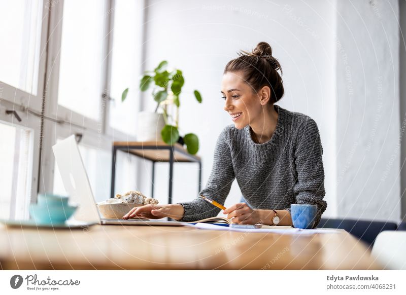 Kreative junge Frau arbeitet am Laptop in ihrem Studio Jahrtausende Schüler Hipster im Innenbereich Loft Fenster natürlich Mädchen Erwachsener eine attraktiv