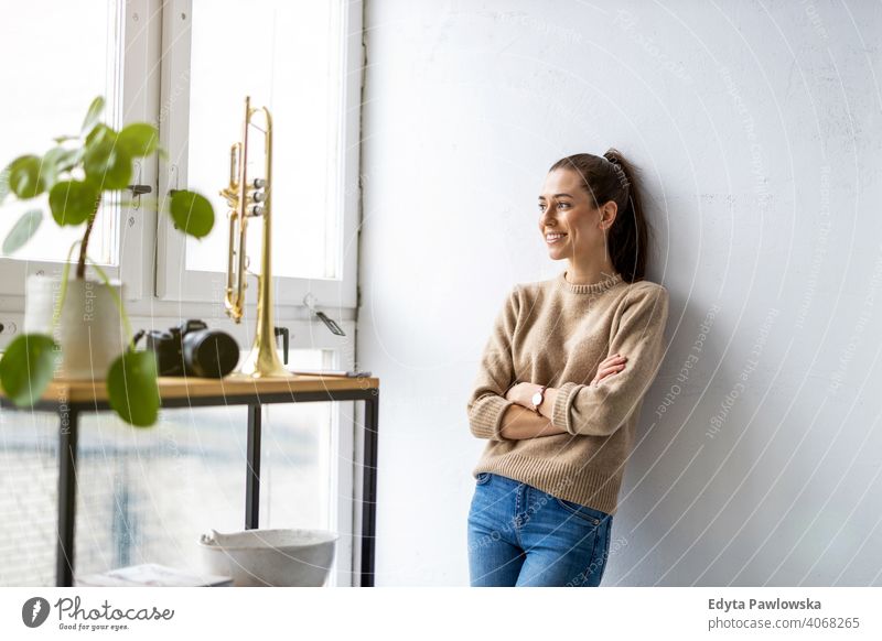 Porträt einer lächelnden kreativen Frau in einem modernen Loft-Raum Jahrtausende Schüler Hipster im Innenbereich Fenster natürlich Mädchen Erwachsener attraktiv