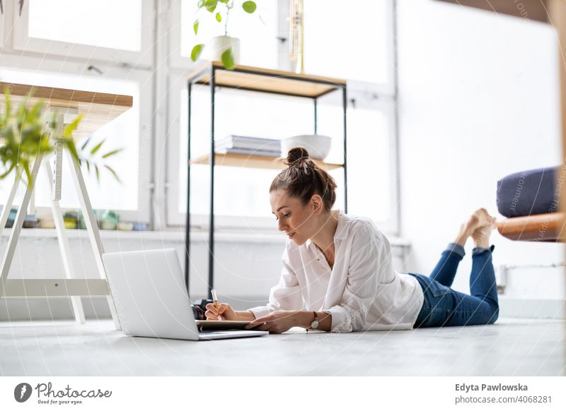 Kreative junge Frau arbeitet am Laptop in ihrem Studio Jahrtausende Schüler Hipster im Innenbereich Loft Fenster natürlich Mädchen Erwachsener eine attraktiv