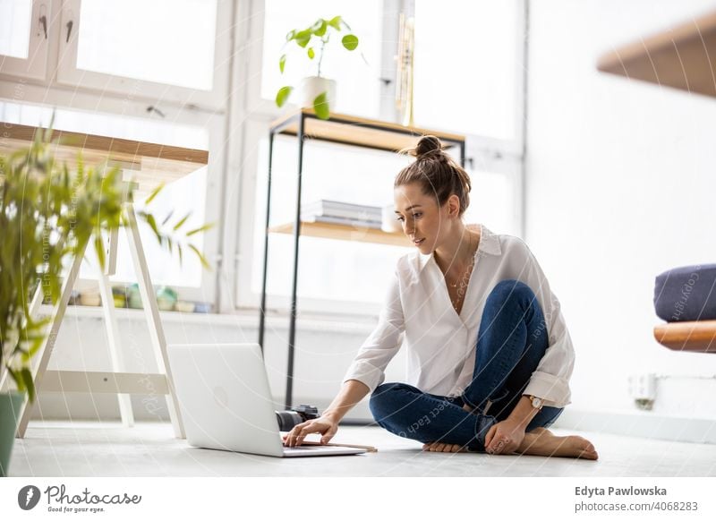 Kreative junge Frau arbeitet am Laptop in ihrem Studio Jahrtausende Schüler Hipster im Innenbereich Loft Fenster natürlich Mädchen Erwachsener eine attraktiv