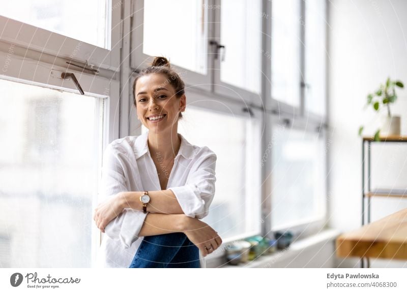 Porträt einer lächelnden kreativen Frau in einem modernen Loft-Raum Jahrtausende Schüler Hipster im Innenbereich Fenster natürlich Mädchen Erwachsener attraktiv