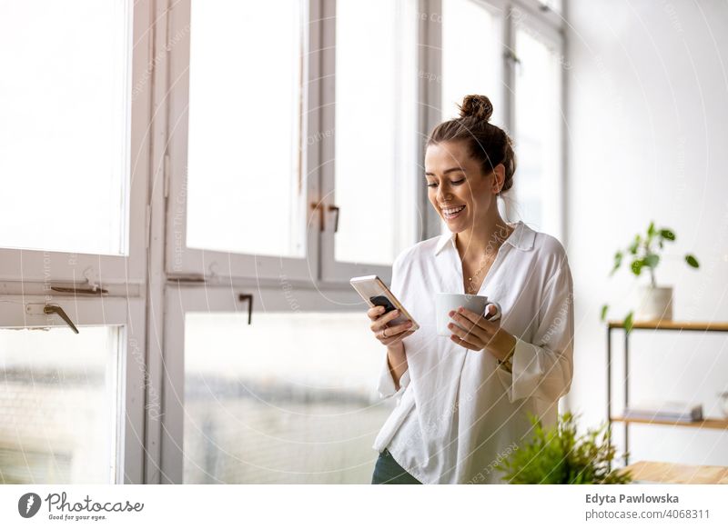 Kreative Geschäftsfrau mit Smartphone im Loft-Büro Jahrtausende Schüler Hipster im Innenbereich Fenster natürlich Mädchen Erwachsener eine attraktiv gelungen