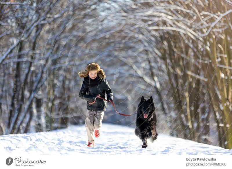 Kleiner Junge genießt den Winter mit seinem Hund schwarz Russisch Aktivität aktiv Abenteuer Tag männlich Begleiter Pflege im Freien Wald Schönheit Frost Natur