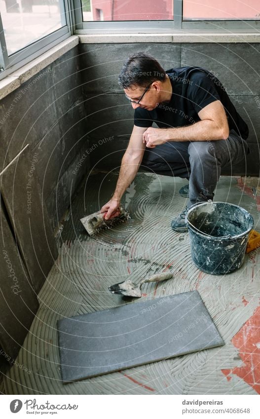 Handwerker beim Verlegen von Fliesen auf einer Terrasse Maurer Heimwerker Reform Fliesen u. Kacheln Installation Stock Flugzeugwartung Fliesenleger