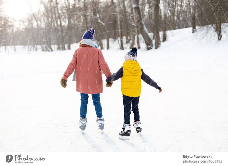 Mutter und Sohn beim Schlittschuhlaufen auf gefrorenem Teich Tochter Saison Zusammensein heiter Spaß Kind Menschen Park Feiertag Wald Kindheit Frau Mädchen