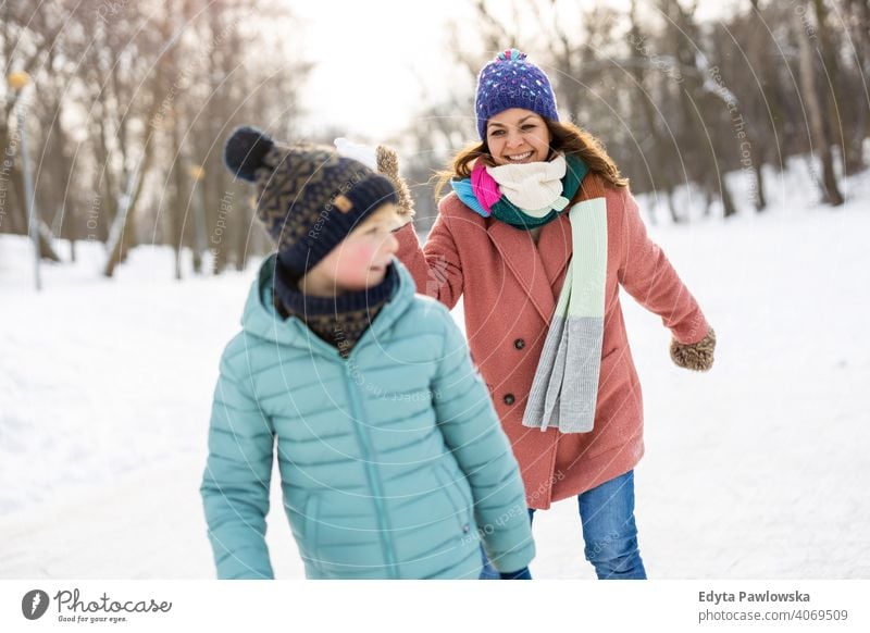 Mutter und Kind mit Schneeballschlacht im Winter Park Sohn Tochter Saison Zusammensein gefroren heiter Spaß Menschen Feiertag Wald Kindheit Frau Mädchen Natur