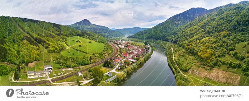 Dorf, Fluss und Straße in Bergtal. Grüne Bergwiesen und Hügel. Kraľoviansky Mäander auf Fluss Bar. Frühling-Panorama Berge u. Gebirge Tatra Wiese Landschaft