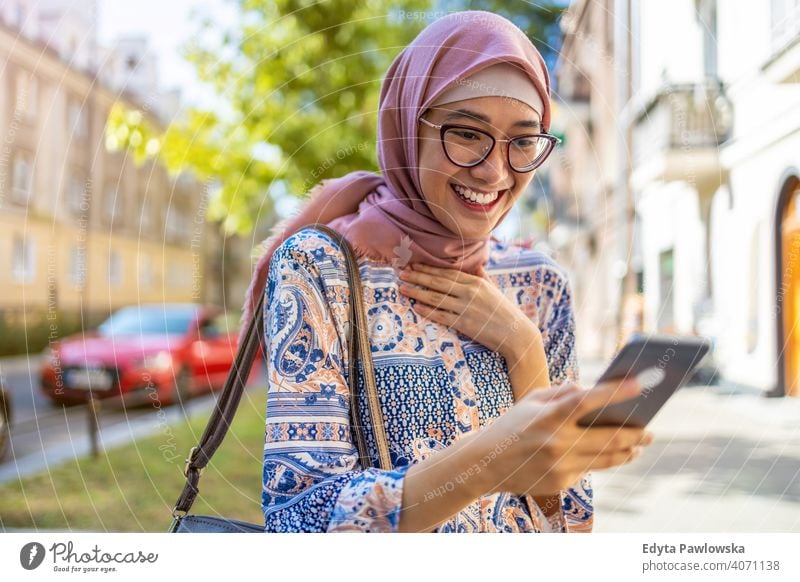 Lächelnde junge muslimische Frau mit Handy im Freien Hijab Kopftuch Islam arabisch Sommer Mädchen Menschen junger Erwachsener Lifestyle aktiv tausendjährig