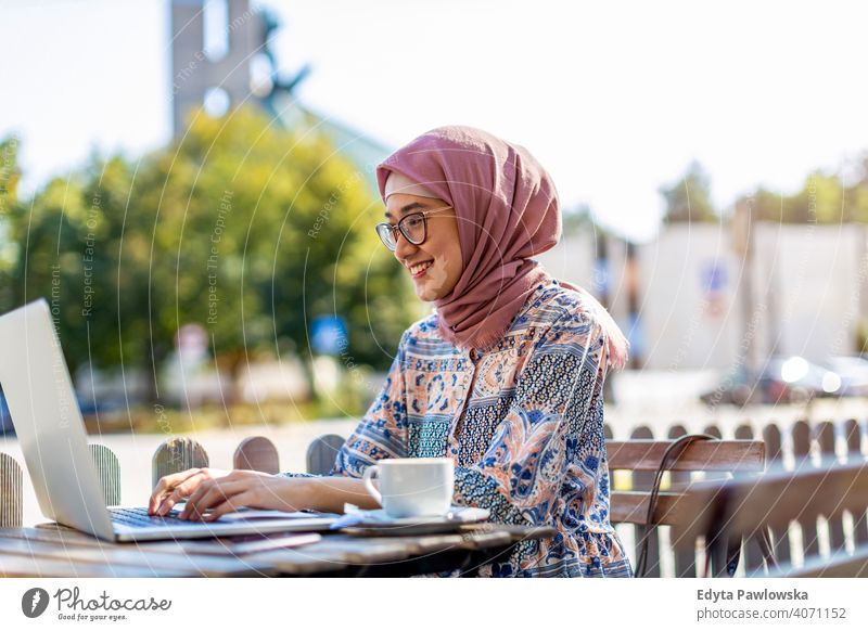 Junge muslimische Frau, die einen Laptop in einem Straßencafé benutzt Hijab Kopftuch Islam arabisch Sommer Mädchen Menschen junger Erwachsener Lifestyle aktiv