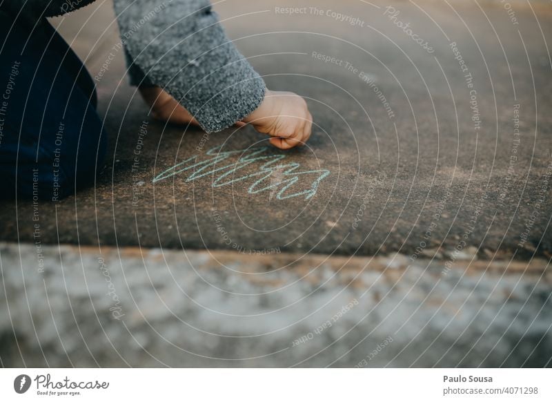 Kind zeichnet mit farbiger Kreide auf dem Boden Kreidezeichnung Kreativität Spielen Zeichnung Kindheit Straße zeichnen Strassenmalerei Freude Asphalt