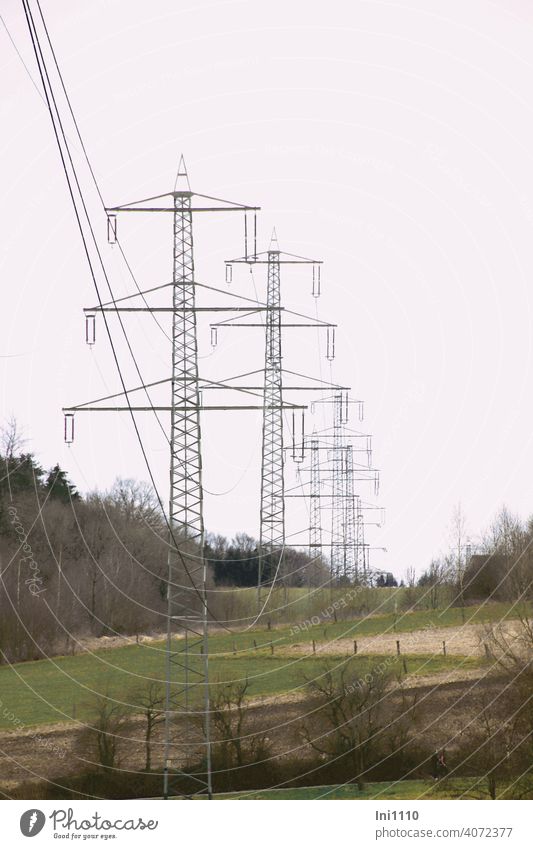 eine Reihe von Metall Strommasten in der Landschaft bei trübem Wetter Tannenmast CO2 Hochspannung Stromleitungen Elektrizität Ernergie Technik & Technologie