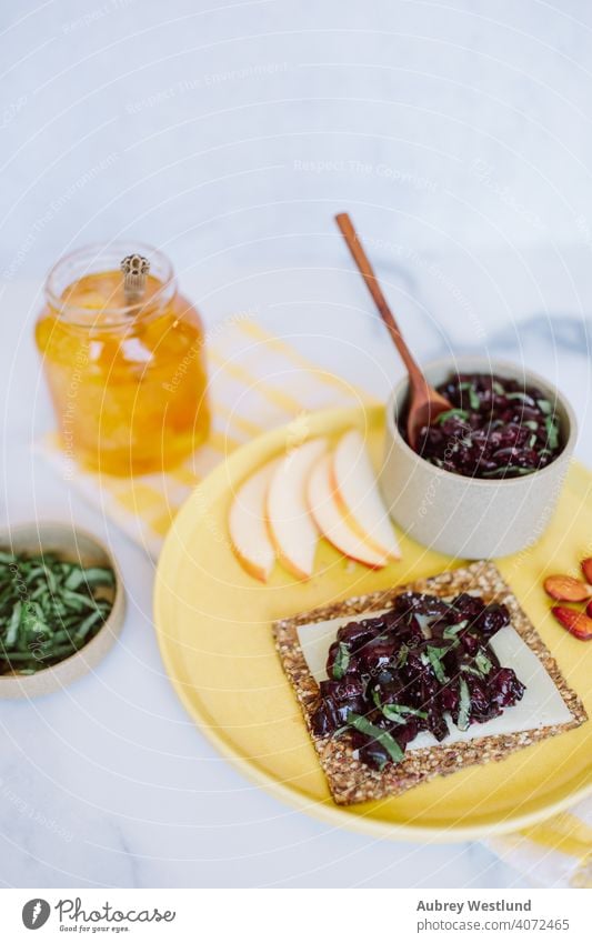 Sommer-Kirsch-Relish-Snack auf einem Körnercracker Mandeln Amuse-Gueule Vorspeisen Äpfel Sortiment Hintergrund Basilikum Beeren Holzplatte Charcuterie