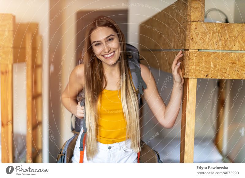 Lächelnde junge Frau mit Rucksack in der Jugendherberge airbnb Miete reisen Tourist Herberge Gästehaus Ferien Reise flach Backpacker besuchen Gepäck Schüler