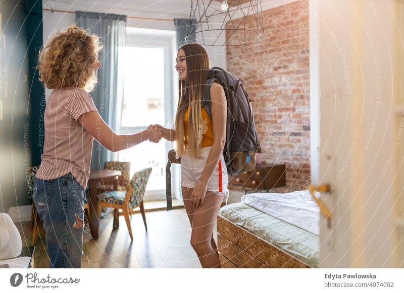 Gastgeber empfängt weiblichen Gast in der Mietwohnung airbnb Miete reisen Tourist Herberge Gästehaus Ferien Reise flach Rucksack Backpacker besuchen Gepäck