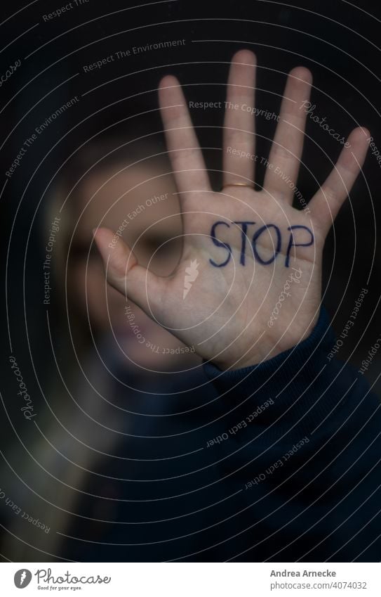 Stop! Frau hält Ihre Hand, auf der Stop steht, gegen eine Scheibe. Halt Grenze stoppen Handfläche Mensch Ablehnung Grenzen setzen nein sagen aufhören beenden