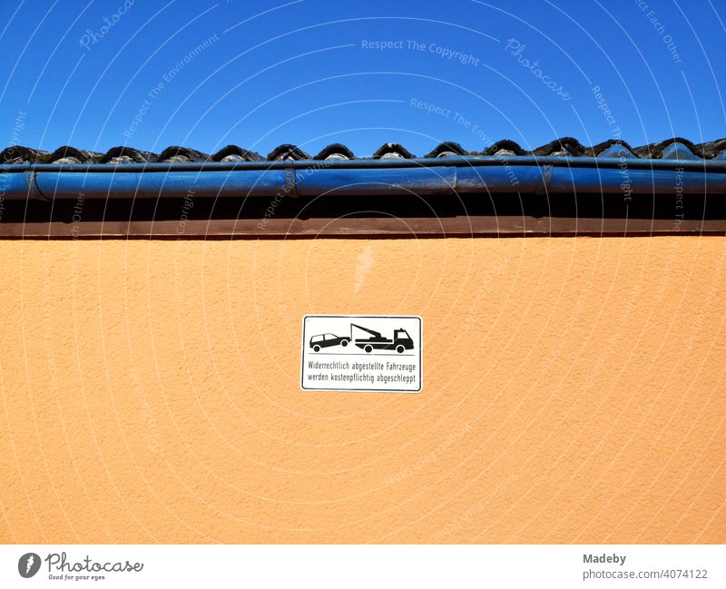 Hinweisschild für Falschparker an einer Fassade in Apricot bei blauem Himmel und Sonnenschein im Sommer in Oerlinghausen bei Bielefeld am Hermannsweg im Teutoburger Wald in Ostwestfalen-Lippe