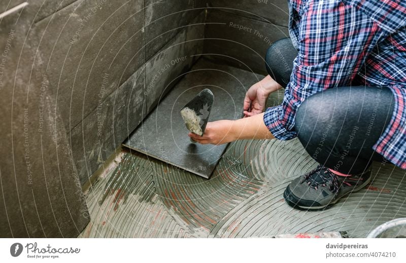 Handarbeiterin beim Verlegen eines neuen Fliesenbodens Bauherr unkenntlich Frau Reform Verlegung leichte Stöße Fliesen u. Kacheln Spachtel Wasserhahn