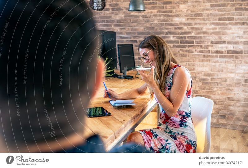 Büroangestellter, der mit einem Mobiltelefon mit Lautsprecher spricht Geschäftsfrau sprechender Lautsprecher Mobile Lächeln Mitarbeiter Blick Handy Mitteilung