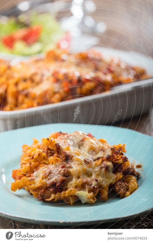 gratinierte Pasta mit Salat auf Holz rigatoni gebacken Käse rustikal Auflauf Sauce Tomaten Bolognaise Fleisch Essen ragu hausgemacht italien Parmesan bolognese