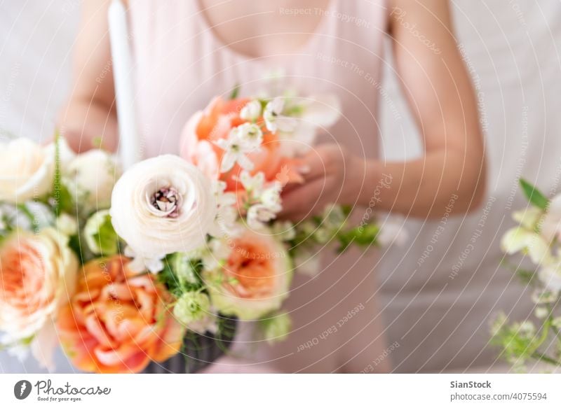 Frau berührt mit den Händen einen Blumenstrauß. Tisch jung Kaukasier Halt Beteiligung Hand Kleid weiß Vase Kerzen weich Licht Dekoration & Verzierung