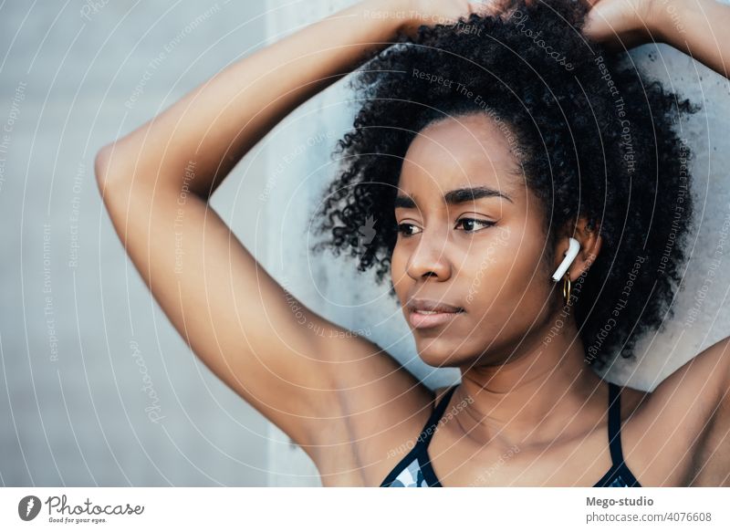 Afro-Athletische Frau im Freien stehend. Fitness Sport Übung aussruhen Pause Ohrstöpsel genießend Erholung Freizeit Großstadt sportlich Sportlerin aktiv