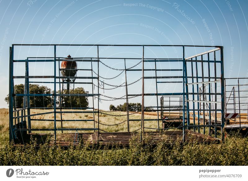 leerer Heuwagen bei der Ernte und im Hintergrund steht ein alter Wasserturm Feld Sommer Natur Landschaft Wiese Gras Stroh Ackerbau ländlich Bauernhof