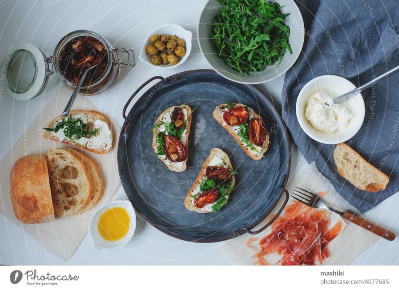 traditionelle italienische Bruschetta - Brottoast mit sonnengetrockneten Tomaten, Frischkäse, Olivenöl und Rucola. Belegtes Brot Lebensmittel Zuprosten Snack