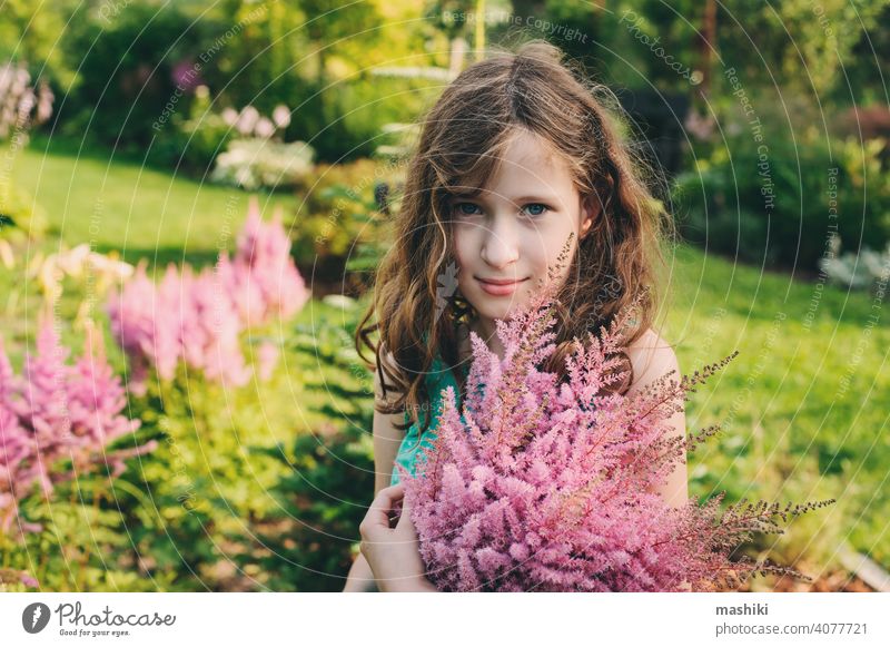 glückliches Kind Mädchen Kommissionierung Bouquet von Astilbe Blumen im Sommer Garten Natur Kindheit im Freien Glück Fröhlichkeit grün niedlich Spaß wenig