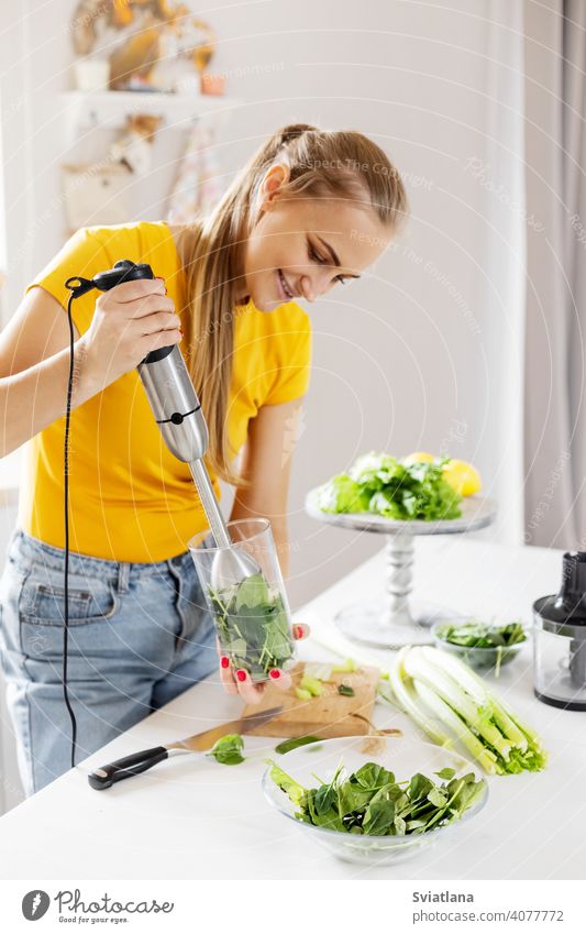 Eine junge Frau macht einen Smoothie aus Gemüse und Obst. Das Konzept einer gesunden Lebensweise und Schlankheit. Mischer grün Gesundheit Lebensmittel Entzug