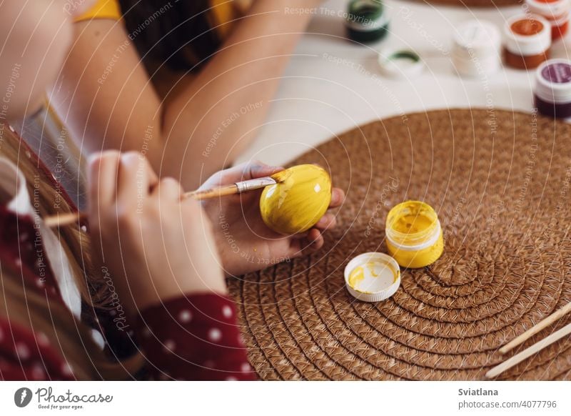 Kleine Blondine zu Hause in der Küche malt Ostereier in verschiedenen Farben für Ostern Frühling Kind Feiertag Vorbereitung Schwestern Bruder Ei hell Familie