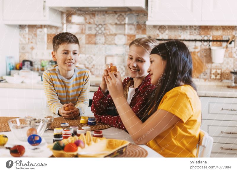 Lustige und fröhliche Kinder sitzen am Tisch malen Ostereier in verschiedenen Farben für Ostern Frühling Feiertag Vorbereitung Schwestern Bruder Ei hell Familie