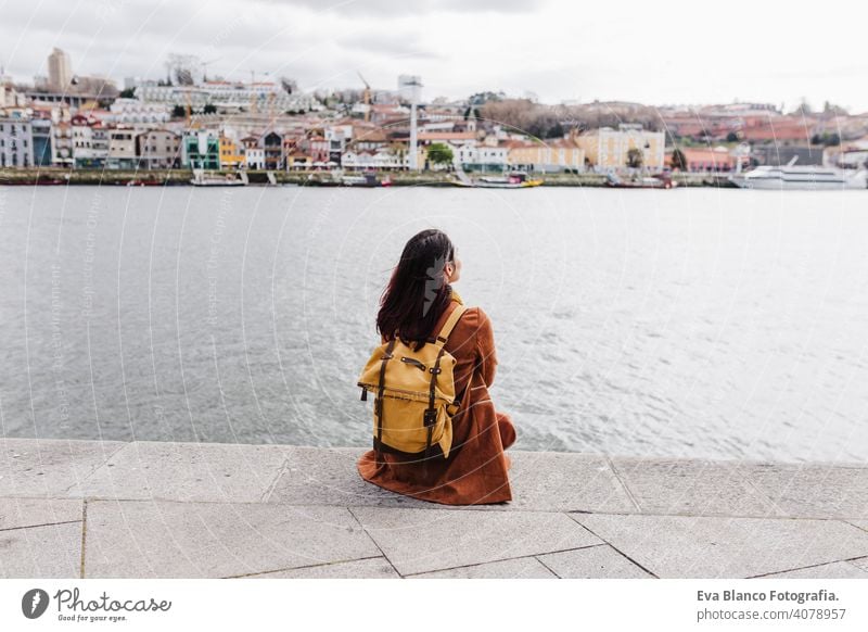 Rückenansicht der jungen schönen Frau sitzt am Fluss bei Sonnenuntergang genießen Porto Ansichten. Reisen Konzept reisen Großstadt Sightseeing urban Kaukasier