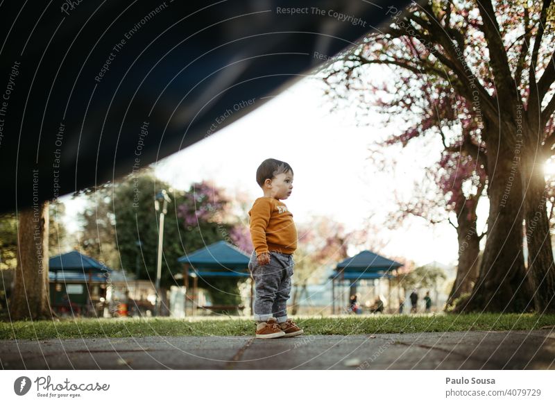 Kind stehend auf dem Spielplatz Junge 1-3 Jahre Kaukasier Stehen Neugier farbenfroh Frühling Frühlingsfarbe Natur authentisch Außenaufnahme Farbfoto Kindheit