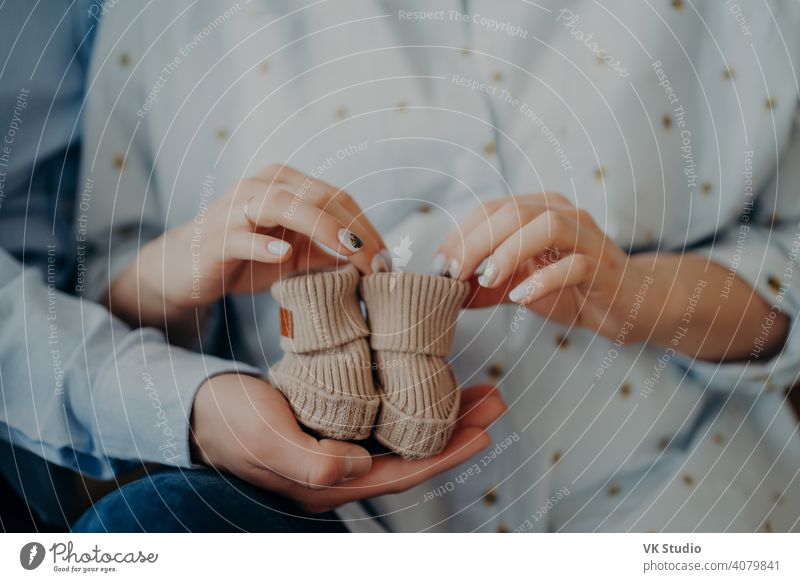 Neugeborenes Baby Stiefel. Cropped Schuss der Zukunft Frau und Mann bereit, Eltern zu werden hält Kinderschuhe. Warten auf Kleinkind. Glückliche Familie Konzept