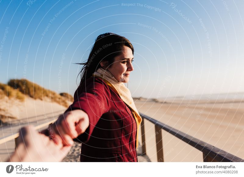 junge kaukasische Frau entspannt am Strand bei Sonnenuntergang. Halten Sie die Hände mit der Kamera, folgen Sie mir. Urlaub und Entspannung Konzept mir folgen