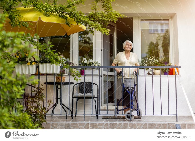 Seniorin mit Rollator auf ihrem Balkon stehend Menschen Frau reif lässig Kaukasier älter heimwärts Haus alt Alterung häusliches Leben Großmutter Rentnerin