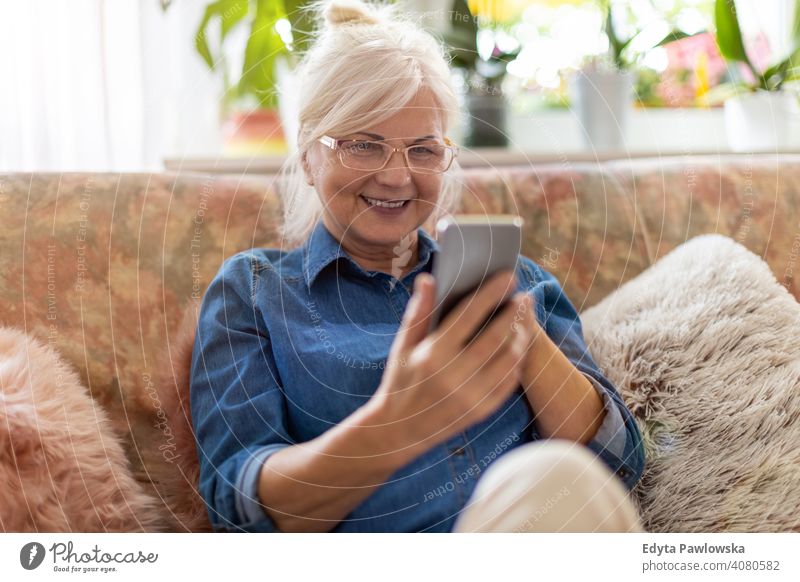 Ältere Frau benutzt Mobiltelefon zu Hause Lächeln Glück genießend Positivität Vitalität Freude Selbstvertrauen Menschen Senior reif lässig Kaukasier älter