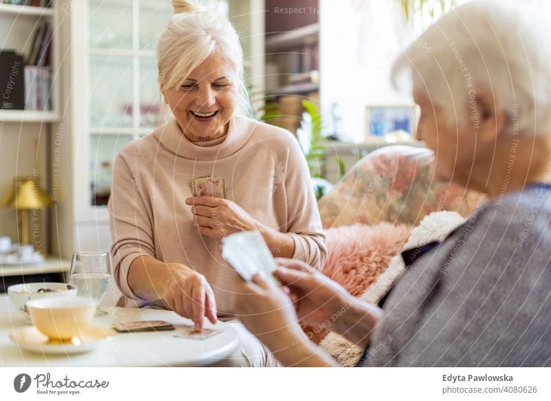 Ältere Frau und ihre erwachsene Tochter spielen Karten zu Hause Lächeln Glück genießend Positivität Vitalität Freude Selbstvertrauen Menschen Senior reif lässig