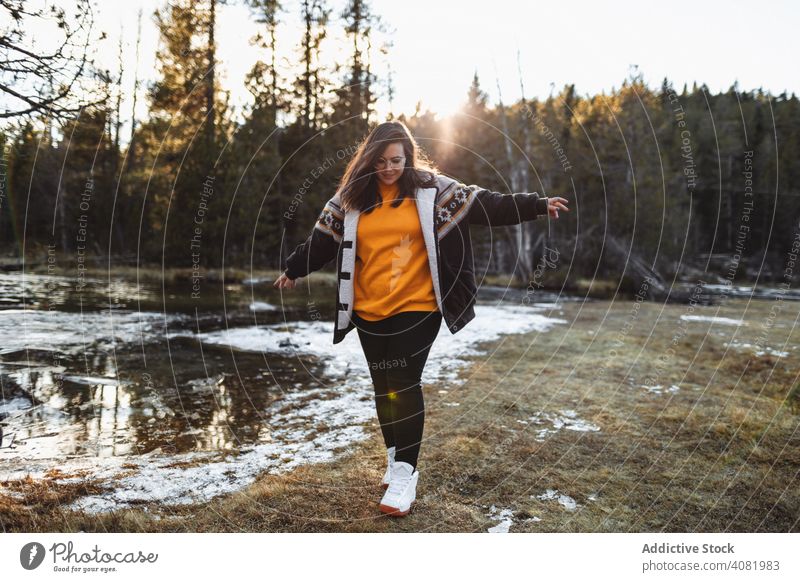 Fröhliche junge Frau am Teich im Wald Glück Wanderer heiter reisend freudig Tourismus Wiese Schnee Wetter Freizeit Fußweg Bäume Sonnenlicht Lifestyle Lächeln