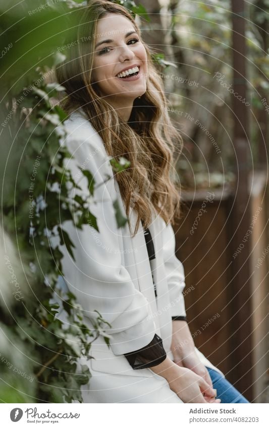 Frau sitzt auf Pflanzer im Garten Pflanzen Sitzen Jeansstoff Stil Hinterhof Straße grün Flora trendy aufgeregt Freude Glück Lifestyle Freizeit organisch