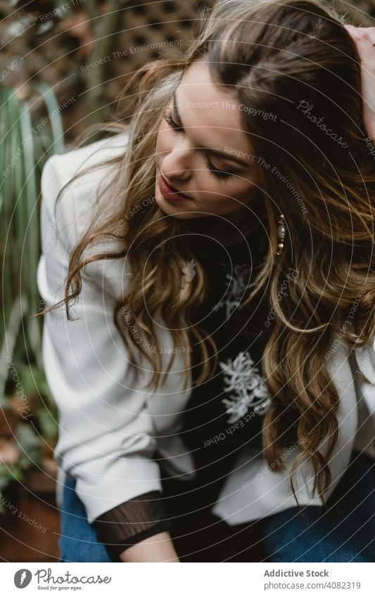 Frau sitzt auf Pflanzer im Garten Pflanzen Sitzen Jeansstoff Stil Hinterhof grün Flora trendy aufgeregt Freude Glück Lifestyle Freizeit organisch natürlich