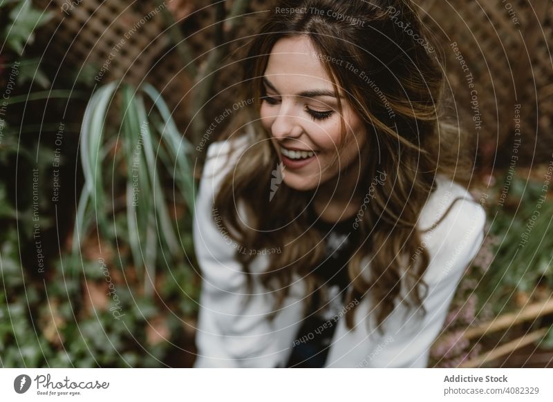 Frau sitzt auf Pflanzer im Garten Pflanzen Sitzen Jeansstoff Stil Hinterhof grün Flora trendy aufgeregt Freude Glück Lifestyle Freizeit organisch natürlich