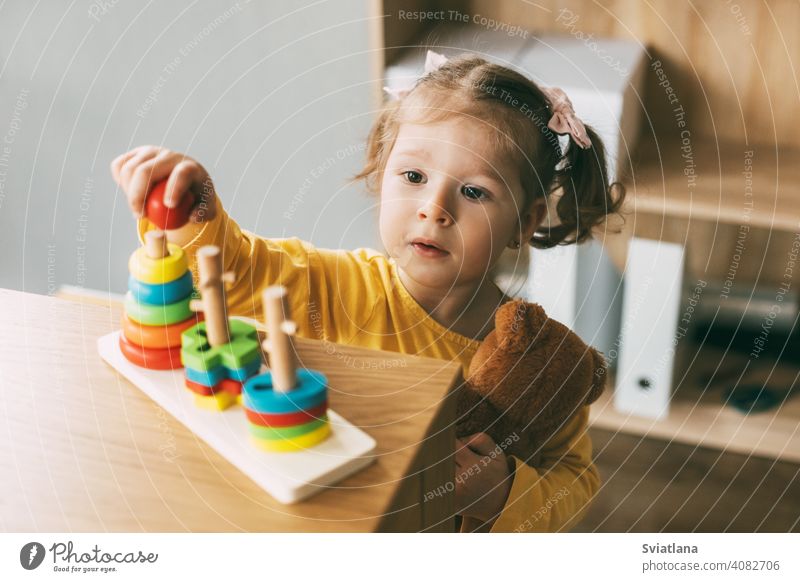 Ein kleines Mädchen sortiert bunte geometrische Formen. Entwicklung der motorischen Fähigkeiten. Entwicklung der motorischen Fähigkeiten und Styling von Figuren.