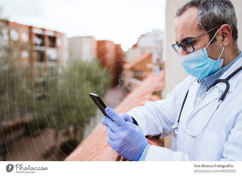 Arzt Mann eine Pause machen, mit Handy. Das Tragen von Schutzhandschuhen, Maske und Stethoskop. coronavirus covid-19 Konzept Corna-Virus Schutzmaske Porträt